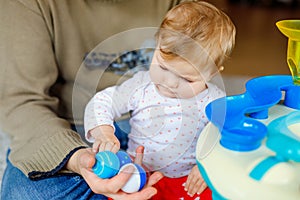 Happy proud young father having fun with baby daughter, family portrait together. Dad playing with baby girl with