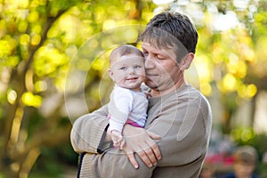 Happy proud young father having fun with newborn baby daughter, family portrait togehter. Dad with baby girl outdoors
