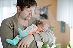 Happy proud young father holding his sleeping newborn baby daughter