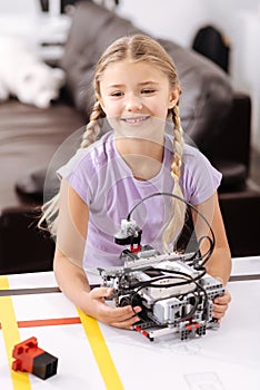 Happy pupil holding electronic robot at school