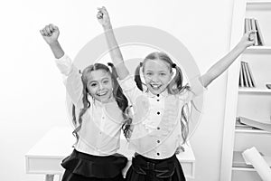 Happy pupils keep hands up in school classroom, victory concept. Little girls celebrate victory. We are the winners