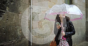 Happy, rain or woman with phone, umbrella or social media in Barcelona city, street or road with smile. Travel