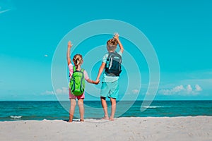 happy ravel on beach, boy and girls with backpack at sea