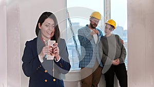 A happy real estate agent holding money in cash - young married couple looking around on the background