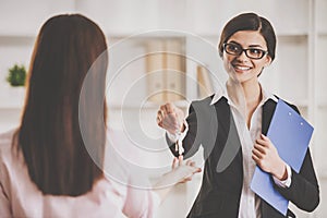 Happy realtor woman giving key to a new owner of an apartment