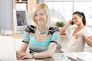 Happy receptionist working on laptop computer