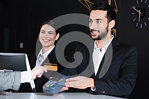 happy receptionists looking at tourist paying