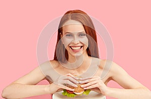 Happy red-haired skinny woman with greedy eyes being ready to eat burger.