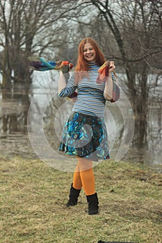 Happy red-haired young girl in bright hippie clothes in orange tights posing and laughing