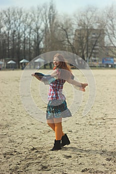 Happy red-haired young girl in bright hippie clothes in orange tights posing and laughing happily whirling and jumping