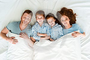 happy redhead family in pajamas lying in bed and smiling