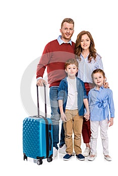 happy redhead family with suitcase standing together and smiling at camera