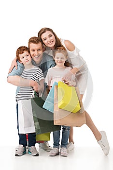 happy redhead family with two kids holding shopping bags and smiling at camera