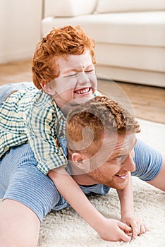 Happy redhead father and son having fun together on carpet at home