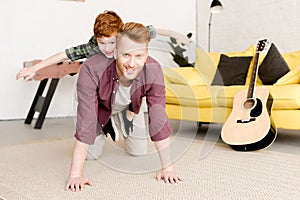 happy redhead father and son smiling at camera while having fun together