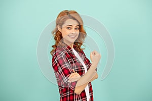 happy redhead woman in checkered shirt threatening with fist on blue background