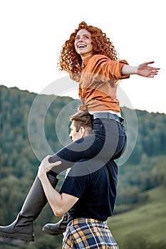 Happy redhead woman and guy trekking in mountains at summer. Positive couple hiking