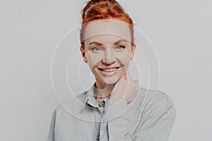 Happy redhead woman looking at camera white toothy smile isolated over grey background