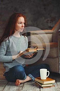 Happy redhead woman relaxing at home in cozy winter or autumn weekend with book