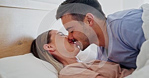 Happy, relax and couple kissing in bed while in conversation for romance or bonding together. Smile, love and young man