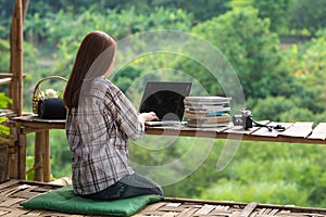 Happy relaxed asian young woman sitting and working on a laptop in the midst of nature photo