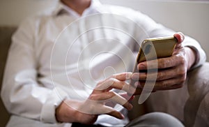 Happy relaxed businessman sitting on couch at home holding smartphone,