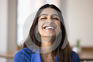 Happy relaxed carefree Indian woman laughing with closed eyes