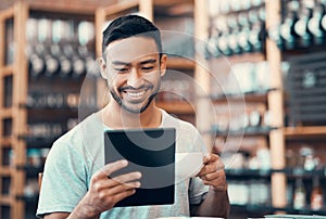 Happy, relaxed and carefree man reading social media news on a tablet while enjoying coffee. Young casual guy replying