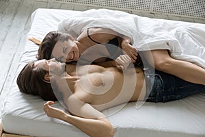 Happy relaxed couple having fun and laughing lying on bed