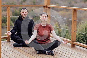 Happy relaxed man and woman doing yoga outdoors. Smiling sportsman sitting in lotus pose