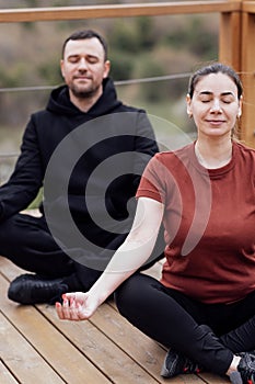 Happy relaxed man and woman doing yoga outdoors. Smiling sportsman sitting in lotus pose