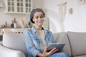 Happy relaxed senior lady watching media content, movie on tablet