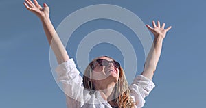 Happy relaxed woman breathing fresh air raising arms over blue sky at summer, Dreaming, freedom and traveling concept