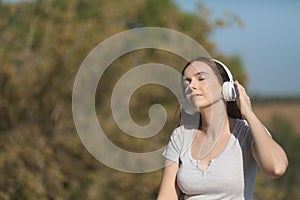 Happy and relaxed woman listens to music with headphones outdoors