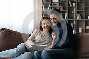 Happy relaxed young family couple using digital computer tablet.