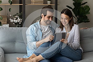 Happy relaxed young family couple using digital computer tablet.