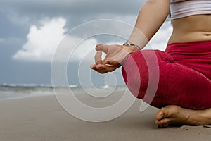 Happy relaxed young woman practicing yoga outdoors at white beach