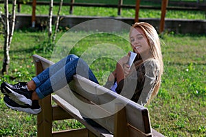 Happy relaxed young woman sitting on a park bench at sunset