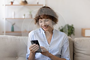 Happy relaxed young woman using smartphone at home.