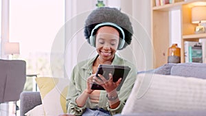 Happy relaxing young woman on sofa playing on tablet. Stressless and carefree female enjoying games relaxed on furniture