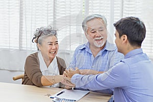 Happy retired Asian senior elderly couple hands shaking business deal and agreement with personal financial advisor or real estate