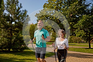 Happy retired couple enjoying pole walk training in urban park