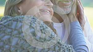 Happy retired couple enjoying romantic date outdoors, woman touching male face