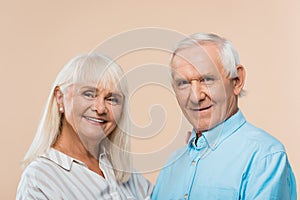 happy retired couple with grey hair looking at camera isolated on beige.