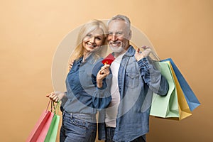 Happy retired couple shopaholics with colorful shopping bags, credit card