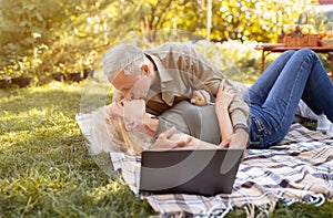 Happy retired couple on summer picnic, kissing and enjoying time together, spending evening outdoors