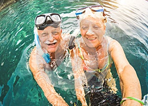 Happy retired couple taking selfie in tropical sea excursion