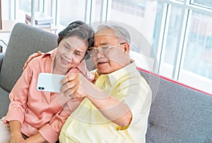 Happy retired couple using mobile phone to take selfie photography picture on a sofa at home