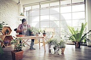 Happy retired man is planting houseplant at home as his hobby for mature leisure activity concept