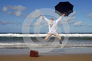 Happy retired senior business man jumping with freedom on a beach vacation